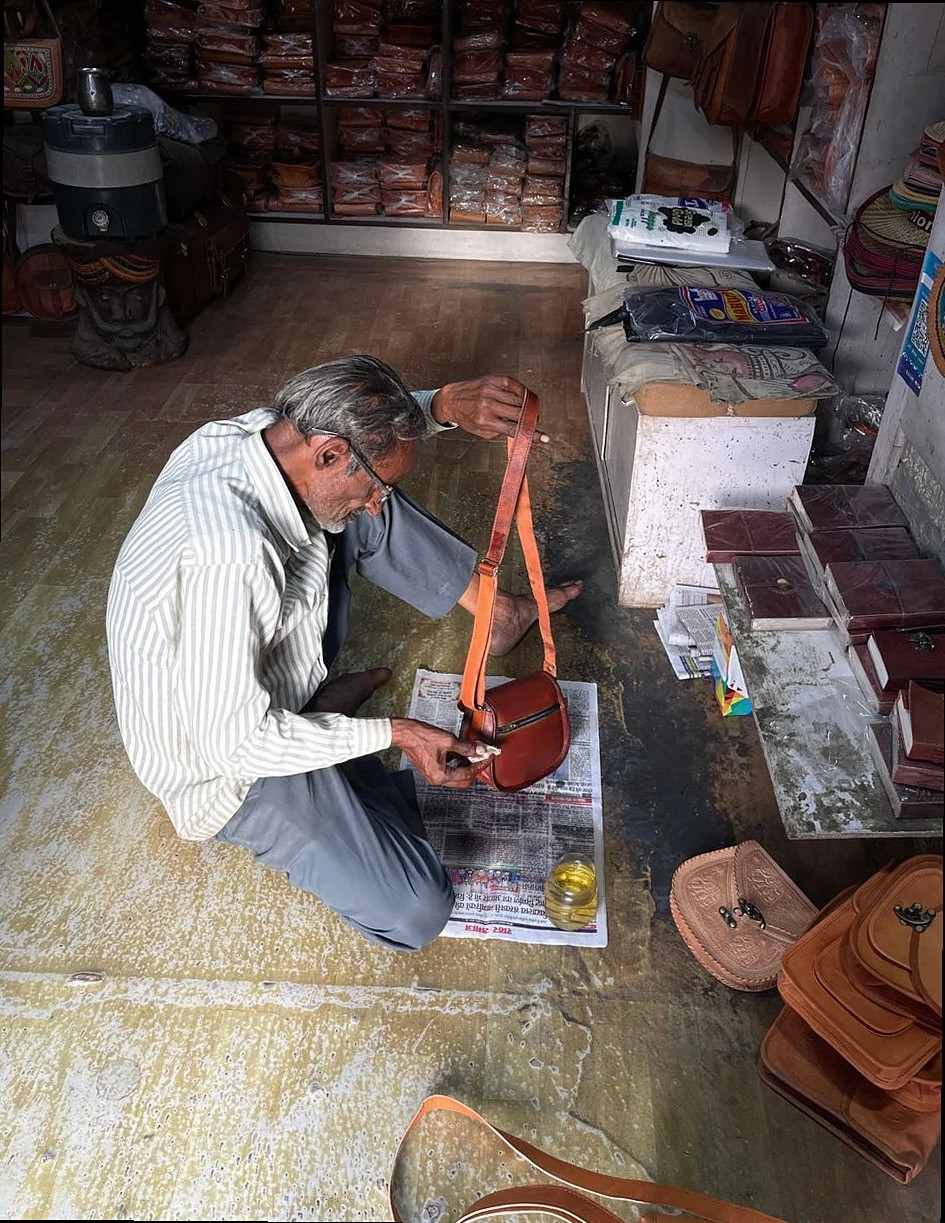 Artisan crafting leather goods in a traditional Jaisalmer shop, India.